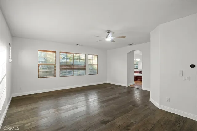 an empty room with wooden floor and ceiling fan