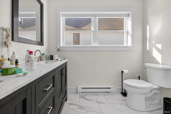 a bathroom with a granite countertop toilet sink and mirror