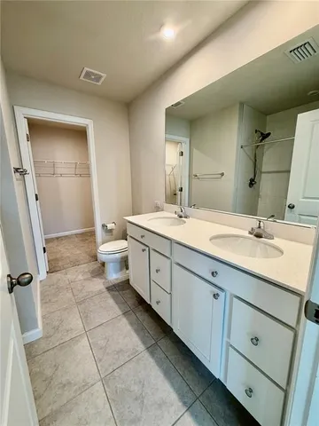 a spacious bathroom with a double vanity sink a mirror and a toilet
