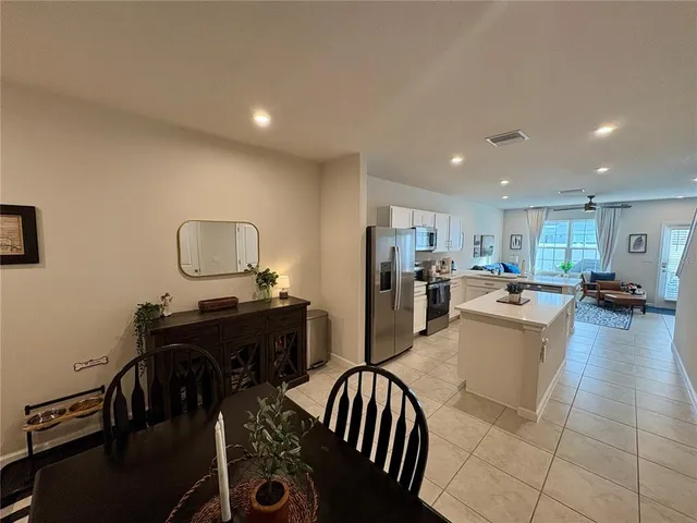 a kitchen with stainless steel appliances granite countertop a refrigerator a stove a sink a dining table and chairs with wooden floor