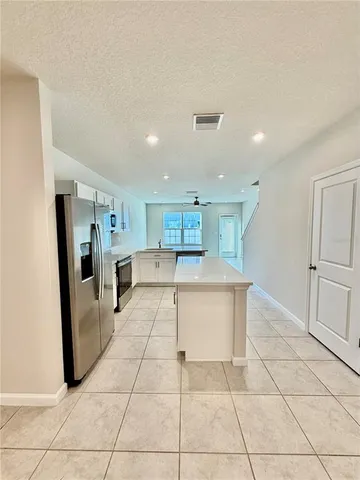 a view of kitchen with refrigerator and white cabinets
