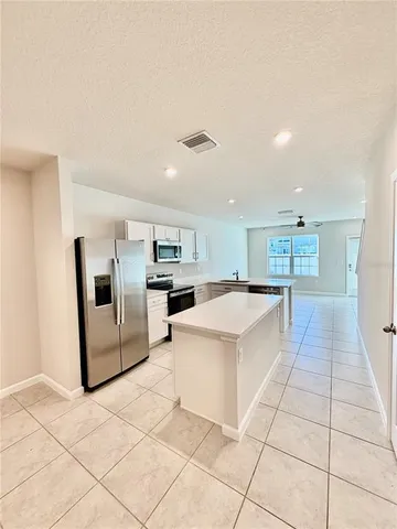 a large white kitchen with a stove a microwave and a refrigerator with white cabinets
