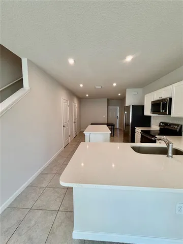 a large white kitchen with stainless steel appliances a large counter top