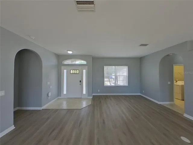 a view of an empty room with window and wooden floor
