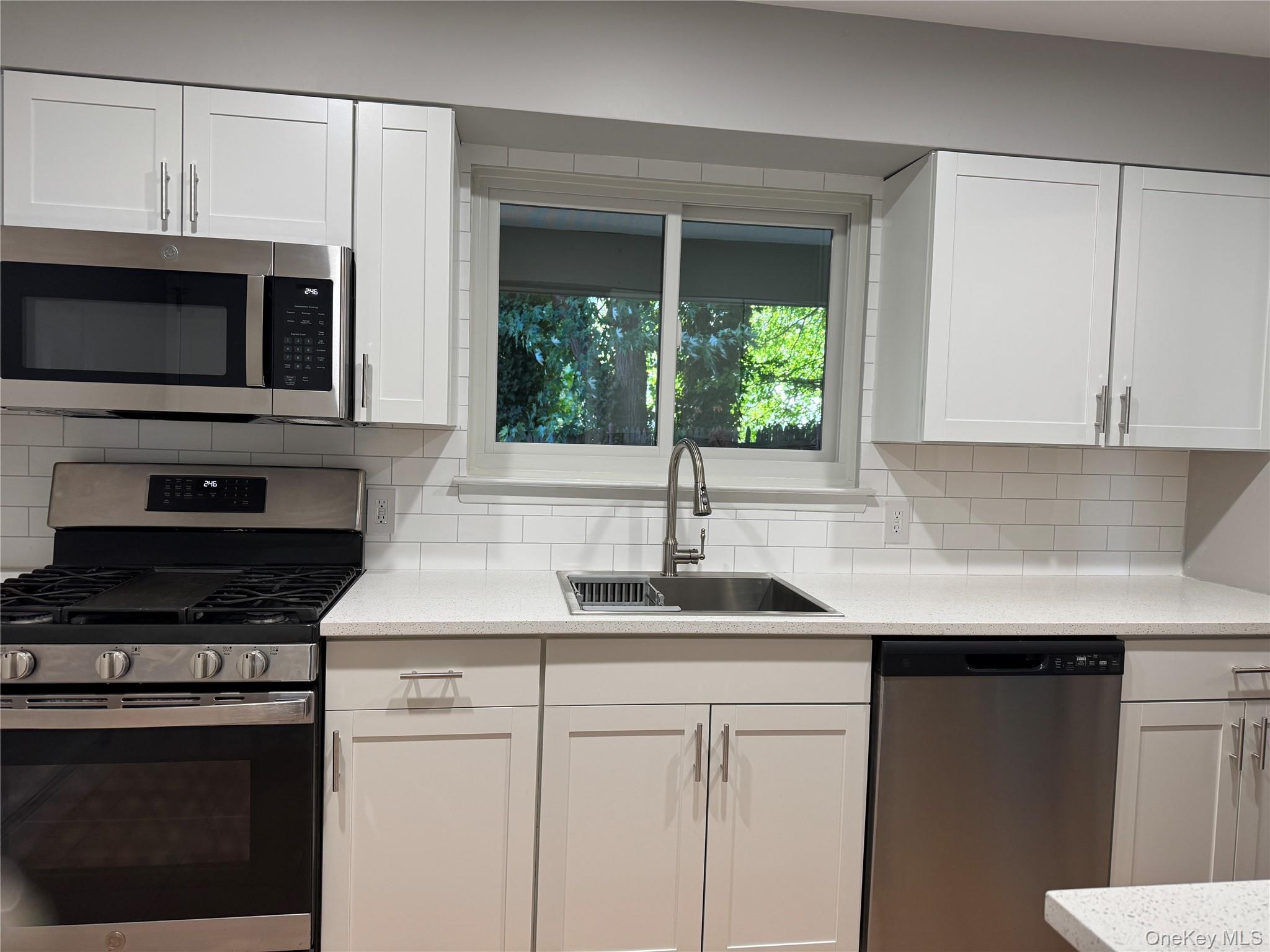 39 B South Norwood Road, Unit RIGHT Port Washington, NY 11050 - Photo 8 of 18 a kitchen with granite countertop a sink stainless steel appliances and cabinets