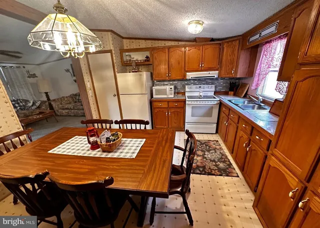 a kitchen with stainless steel appliances granite countertop a sink dishwasher stove a refrigerator a dining table and chairs with wooden floor