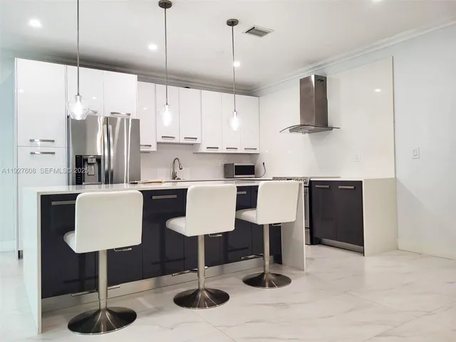 a kitchen with stainless steel appliances kitchen island granite countertop a sink a refrigerator and a stove