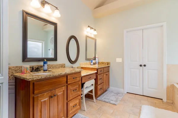 a bathroom with a tub a double vanity sink and mirror