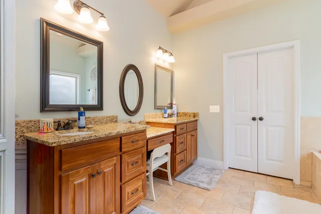 a bathroom with a tub a double vanity sink and mirror