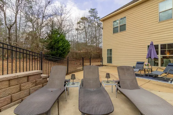 a view of a patio with couches table and chairs and wooden fence
