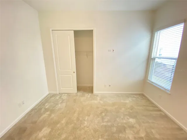 a view of a hallway with wooden floor and a bathroom
