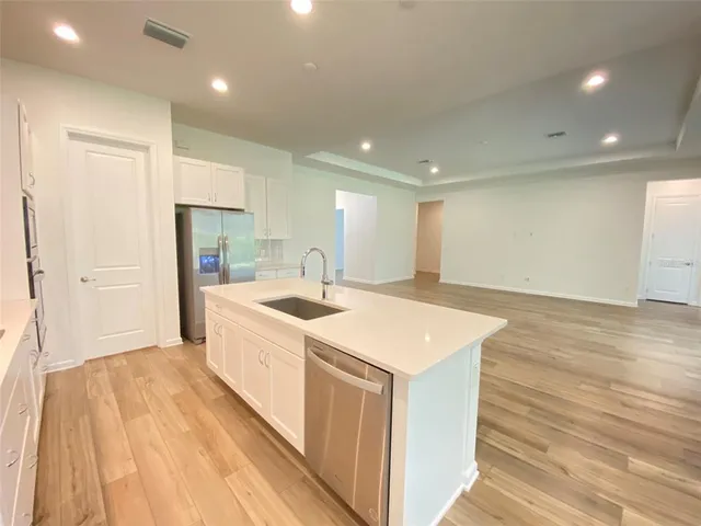 a large kitchen with a sink a refrigerator and a dishwasher