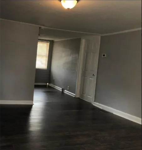 an empty room with wooden floor and windows with curtains