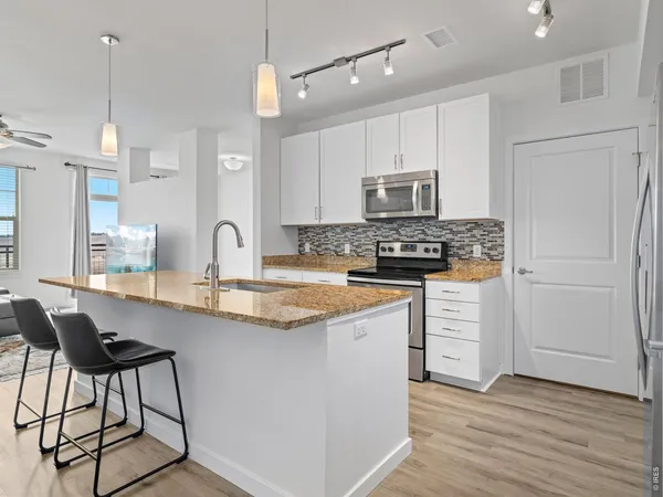 a kitchen with granite countertop a sink stove and refrigerator