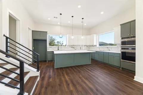 a kitchen with kitchen island wooden floors appliances and cabinets