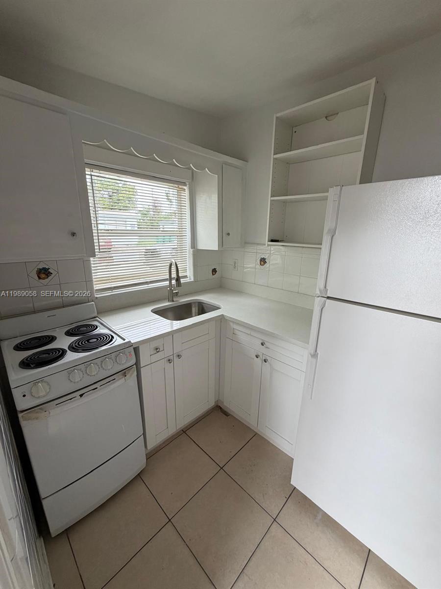5411 Ravenswood Road, Unit 6 Dania Beach, FL 33312 - Photo 2 of 7 a kitchen with a stove white cabinetry and a sink