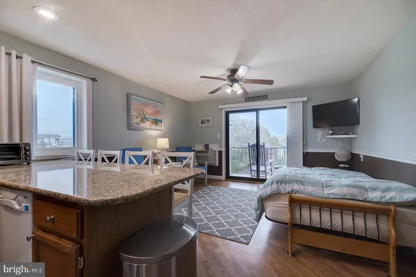 a living room with stainless steel appliances granite countertop furniture a fireplace a flat screen tv and a large window