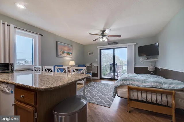 a living room with stainless steel appliances granite countertop furniture a fireplace a flat screen tv and a large window