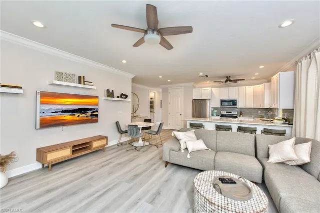 a living room with furniture kitchen view and a flat screen tv