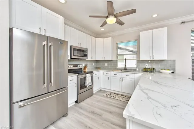 a kitchen with granite countertop a refrigerator a sink a stove a microwave and island with wooden floor