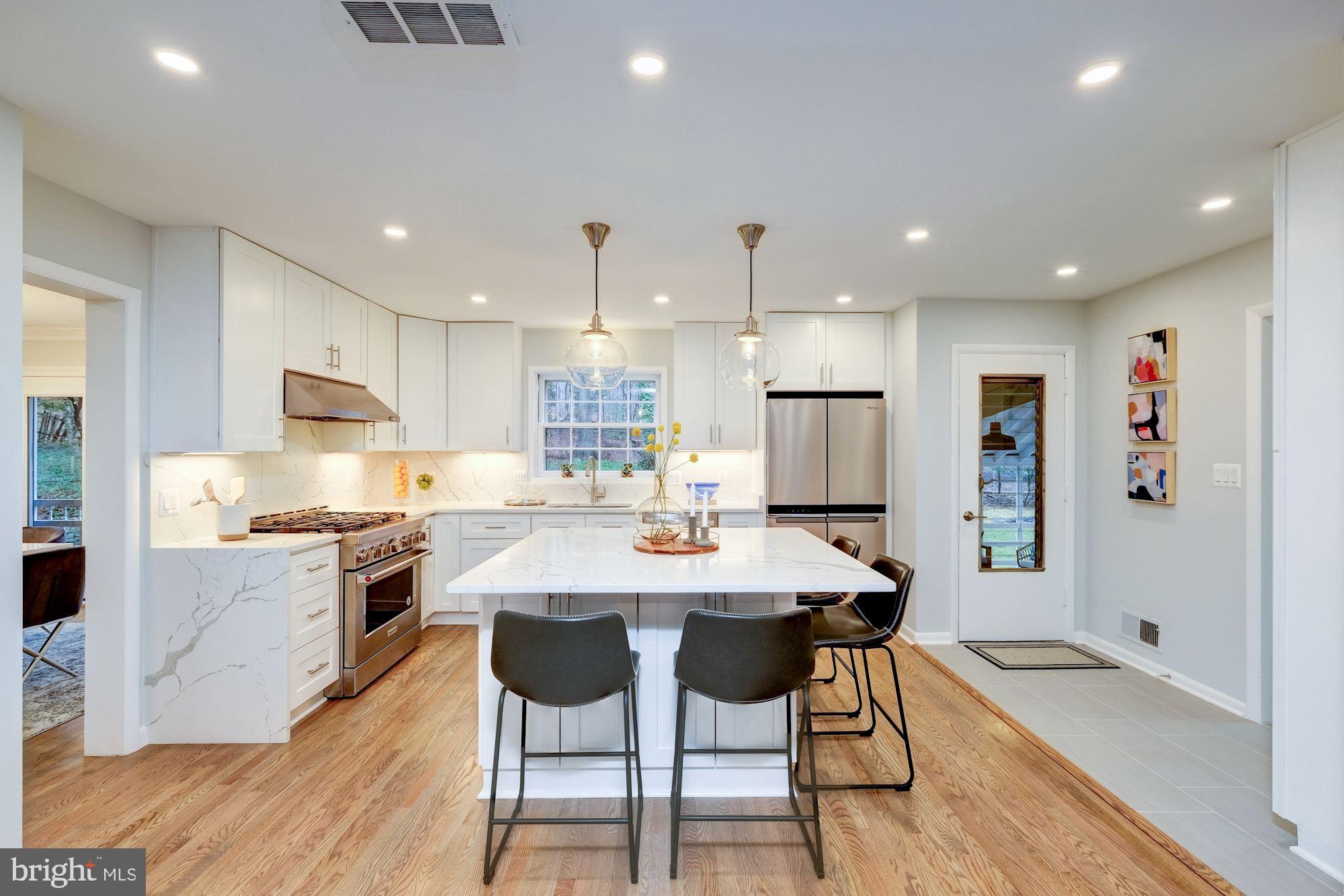 7440 Arrowood Road Bethesda, MD 20817 - Photo 22 of 79 a kitchen with stainless steel appliances kitchen island granite countertop a table chairs stove microwave and cabinets