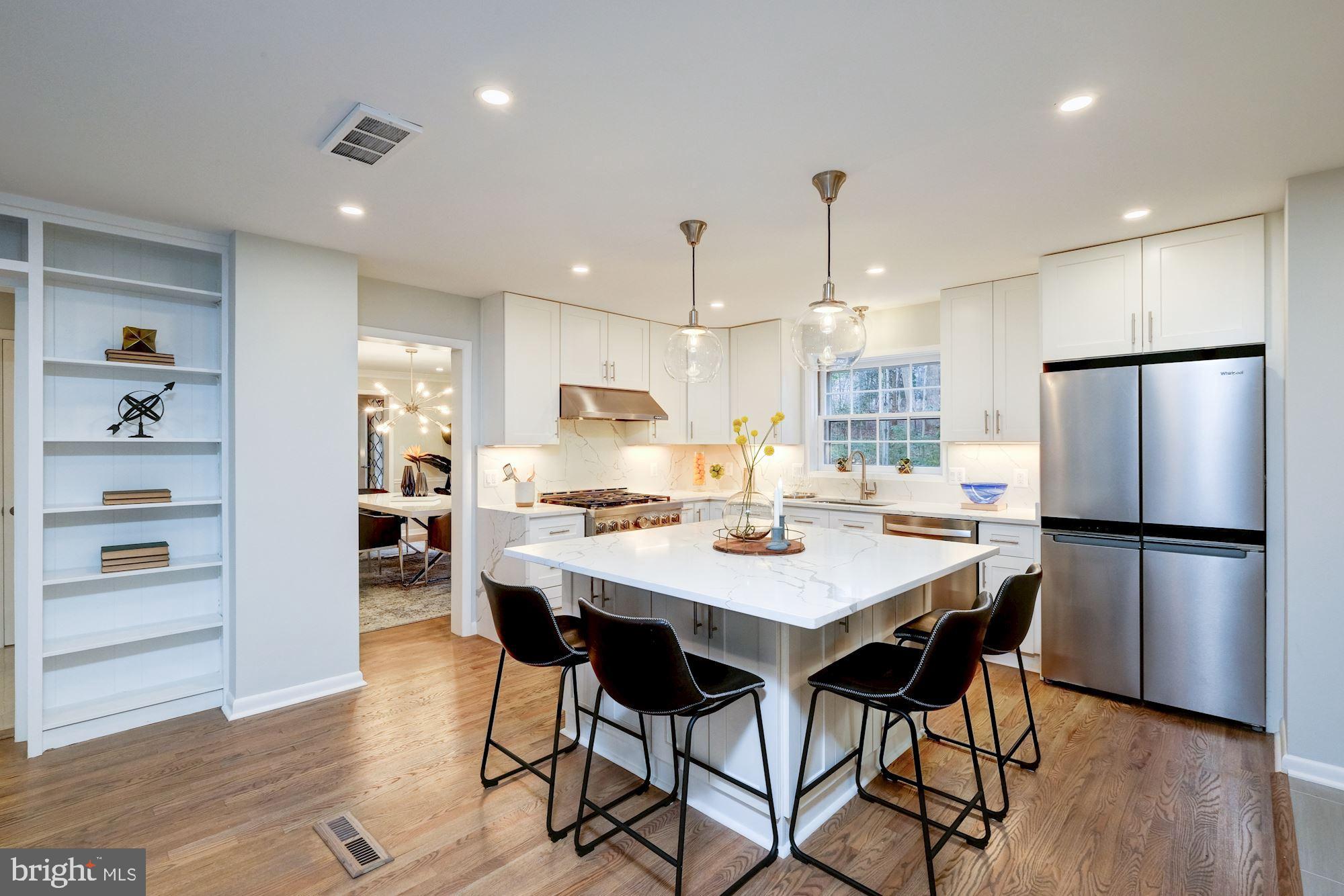 7440 Arrowood Road Bethesda, MD 20817 - Photo 23 of 79 a kitchen with stainless steel appliances kitchen island granite countertop a dining table chairs refrigerator and sink