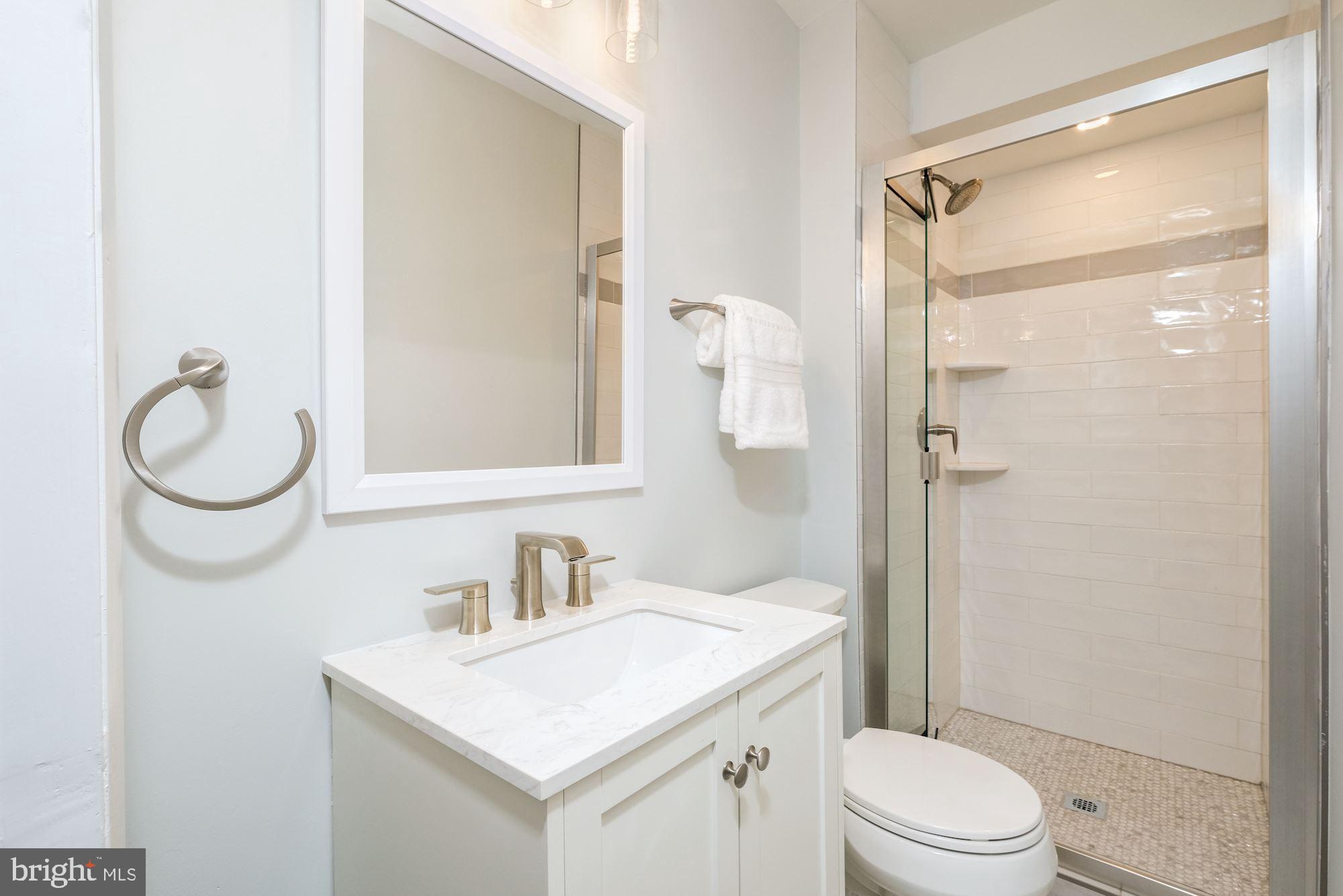 7440 Arrowood Road Bethesda, MD 20817 - Photo 40 of 79 a bathroom with a granite countertop sink toilet mirror vanity and shower