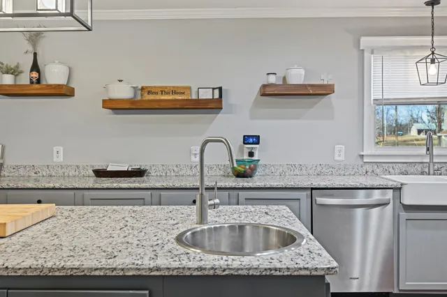 a kitchen with kitchen island granite countertop a sink a counter space and cabinets