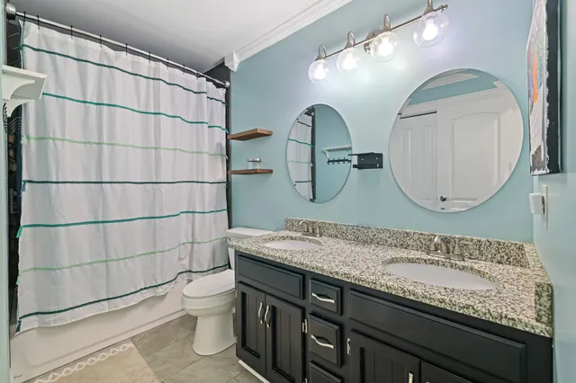 a bathroom with a granite countertop double vanity sink and a mirror