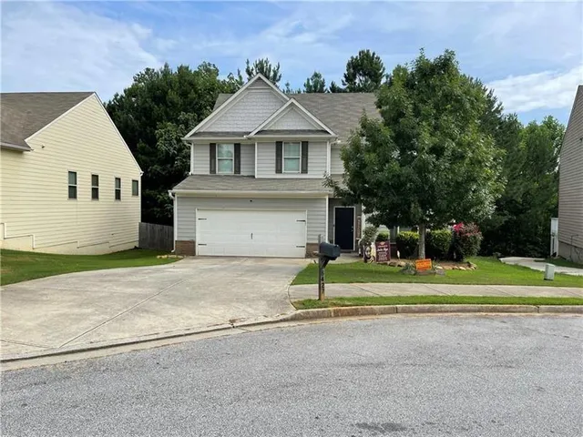 a front view of a house with a yard and trees