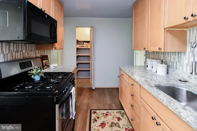 a kitchen with granite countertop a sink stove and cabinets