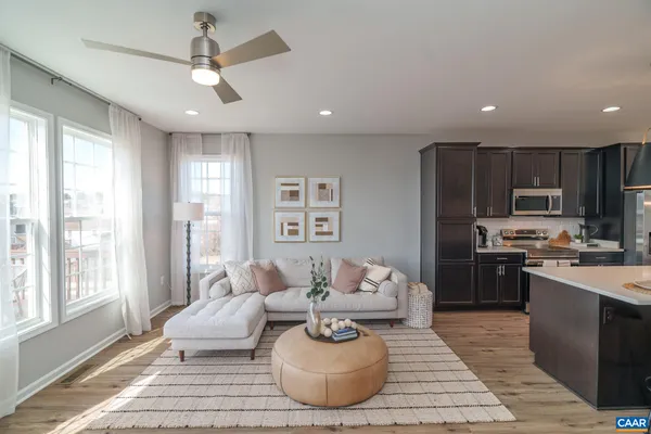 a living room with stainless steel appliances furniture a rug kitchen view and a chandelier