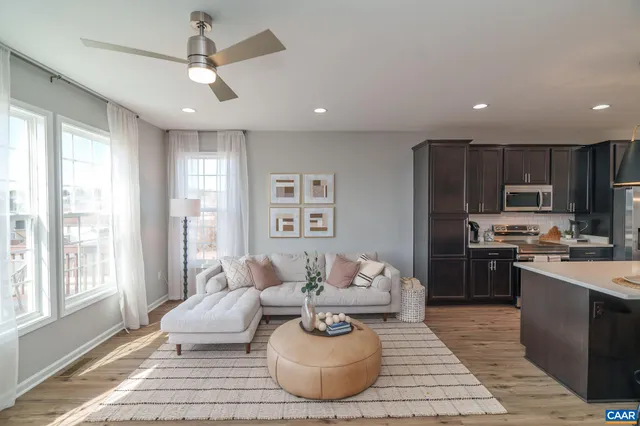 a living room with stainless steel appliances furniture a rug kitchen view and a chandelier