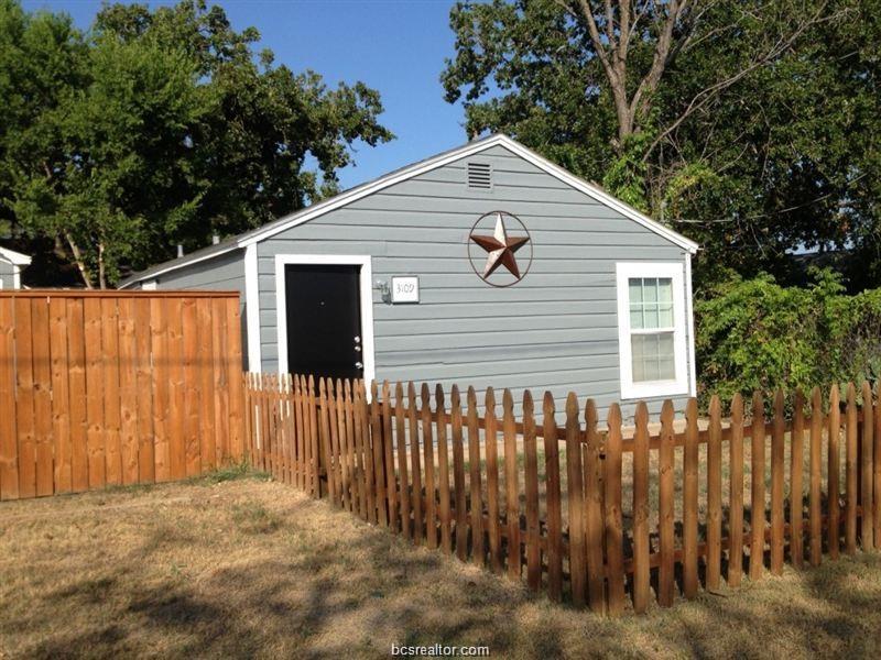 a view of a house with a small yard and wooden fence