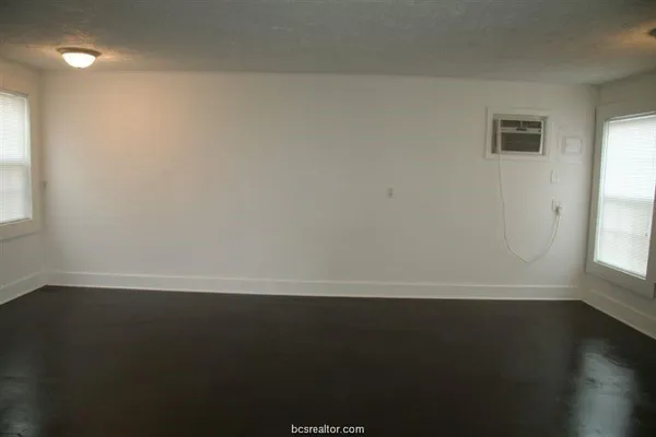 en empty room with wooden floor and windows