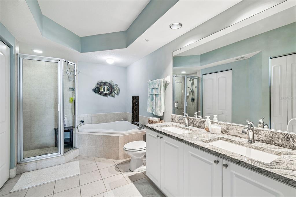 4516 Seagull Drive, Unit 807 New Port Richey, FL 34652 - Photo 28 of 100 a bathroom with a granite countertop sink a toilet a mirror a bathtub and shower