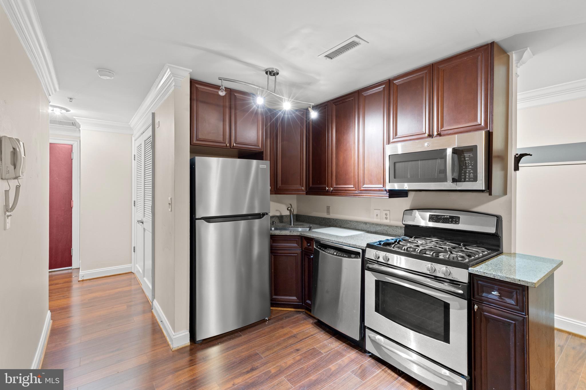 1210 R Street Northwest, Unit B1 Washington, DC 20009 - Photo 6 of 15 a kitchen with wooden cabinets stainless steel appliances and wooden floor