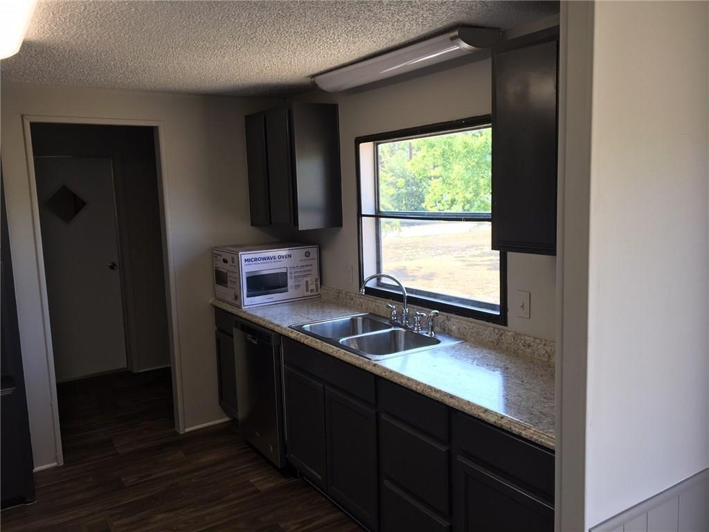 365 Darrell Road Roanoke, TX 76262 - Photo 8 of 22 Kitchen featuring dark wood-finish cabinetry, a double basin stainless steel sink, a stainless steel dishwasher, and mottled light-toned countertops