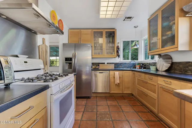 a kitchen with stainless steel appliances granite countertop a stove a sink and a granite counter tops with white cabinets
