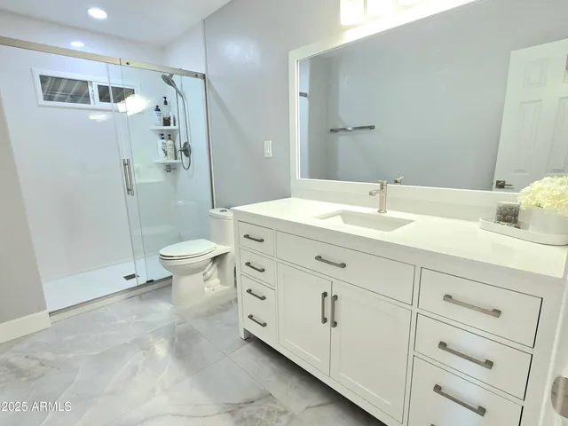 a spacious bathroom with a double vanity sink toilet mirror and shower