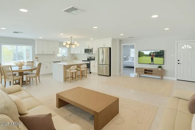a living room with furniture a flat screen tv and kitchen view