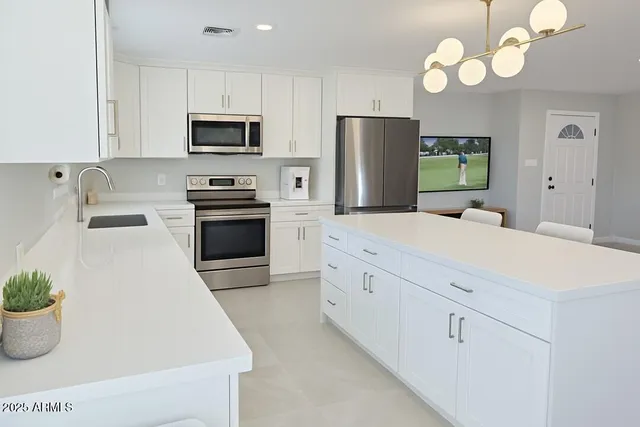 a kitchen with stainless steel appliances a white cabinets wooden floor and a refrigerator