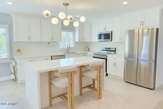 a kitchen with a refrigerator a sink and dishwasher with white cabinets