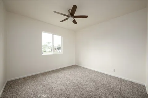 an empty room with a ceiling fan and window