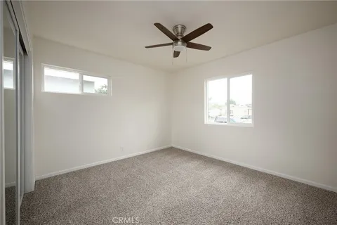 an empty room with windows and fan