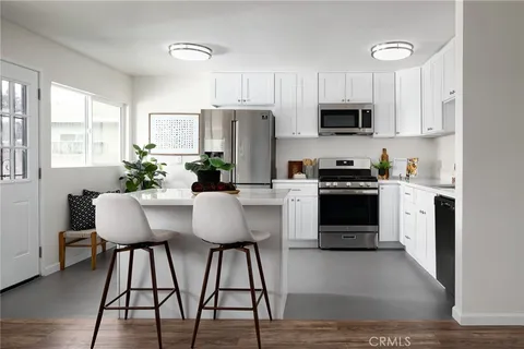 a kitchen with stainless steel appliances kitchen island a table chairs microwave and sink