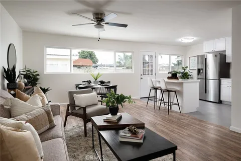 a living room with furniture kitchen view and a window