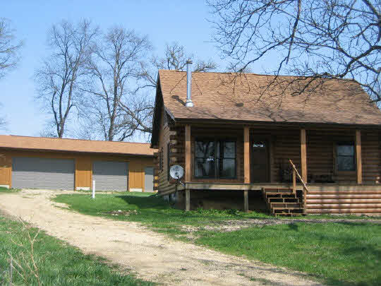 10174 East Brick School Road Davis, IL 61019 - Photo 2 of 5 a view of a house with a large window and a yard with plants and large trees