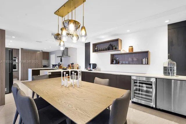 a kitchen with stainless steel appliances granite countertop a table chairs and a refrigerator