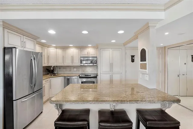 a kitchen with stainless steel appliances granite countertop a kitchen island a stove and a refrigerator